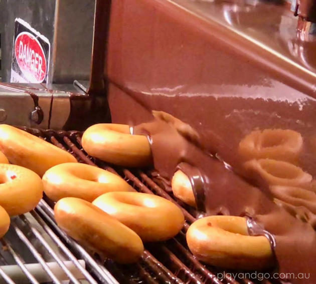 Krispy Kreme doughnuts being glazed in chocolate